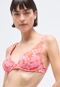 Floral bikini top featuring a pink and orange color scheme, smooth texture, triangle cups, and wide straps, designed for comfort and support.