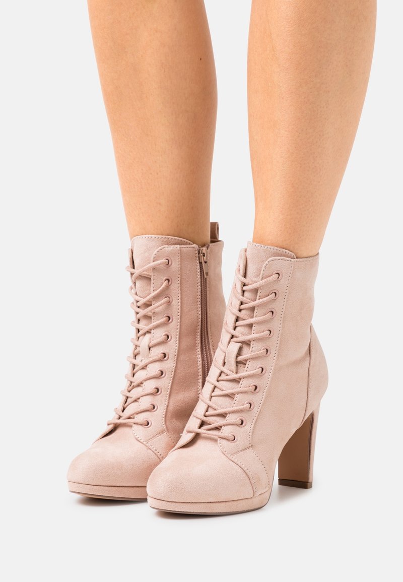 Stivaletti alla caviglia in suede rosa con tacco alto, caratterizzati da un'abertura con lacci e una cerniera laterale per una facile vestibilità. Tessuto liscio con design a punta rotonda.