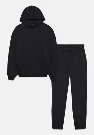 Schwarzes Set aus Kapuzenpullover und Jogginghose, aus weichem Stoff gefertigt. Der Kapuzenpullover hat eine Kordelzugkapuze und Rippbündchen, die Hose hat einen elastischen Bund und Knöchelbündchen.