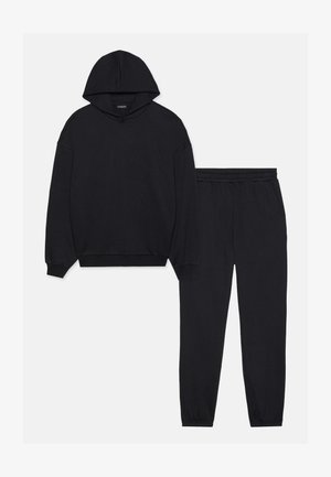 Mustmust ja dressipüksid, valmistatud pehmest kangast. Mustmustil on tõmbluku kapuuts ja soonikkäärid, pükstel on elastne vöökoht ja pahkluuekääred.