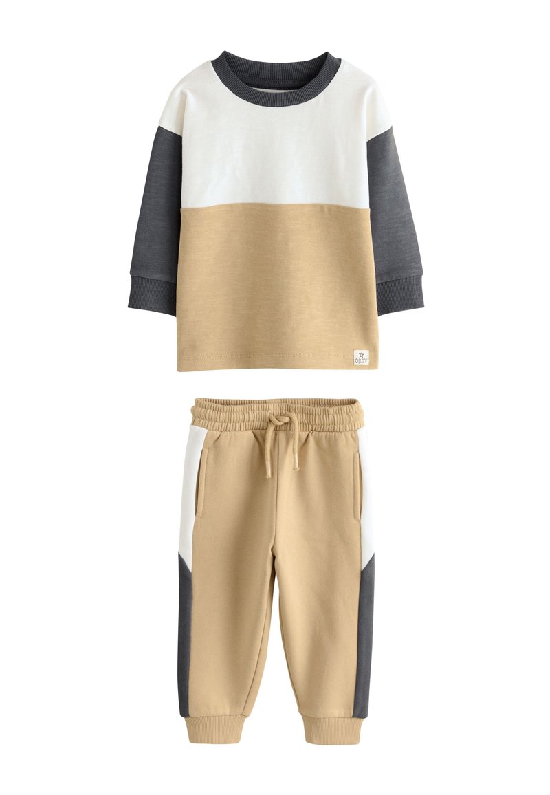 Two-piece set featuring a long-sleeve top in beige, white, and gray, with matching beige pants that have side pockets and color-blocked accents.
