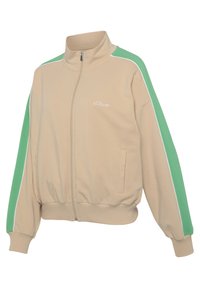 Beige zip-up jacket with green shoulder accents, white piping, and elastic cuffs. Features side pockets and embroidered logo on the chest.