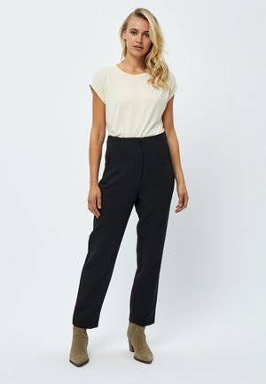 Beige short-sleeve top paired with high-waisted black trousers and ankle boots. Trousers have creased details and a tailored fit.