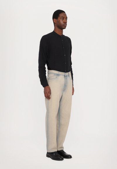 Cardigan nero a bottoni, jeans grigi chiari a gamba affusolata e scarpe di pelle nera. Design semplice con colori a contrasto e vestibilità standard.