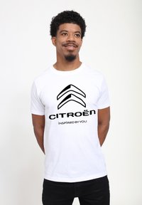 Bílý bavlněný tričko s černým logem Citroën a textem "INSPIRUJEME SE VÁMI" v tučné, moderní typografii. Krátké rukávy a kulatý výstřih.
