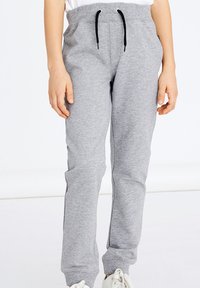Graue Sweatpants aus einem weichen Baumwollmix, mit einem elastischen Bund und schwarzen Kordeln, seitlichen Taschen und einem schmal zulaufenden Bein.