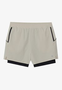 Beige shorts med elastikmidja, sidfickor och en svart underdel. Har en delad nederkant och diskret logotyp på underbenet.