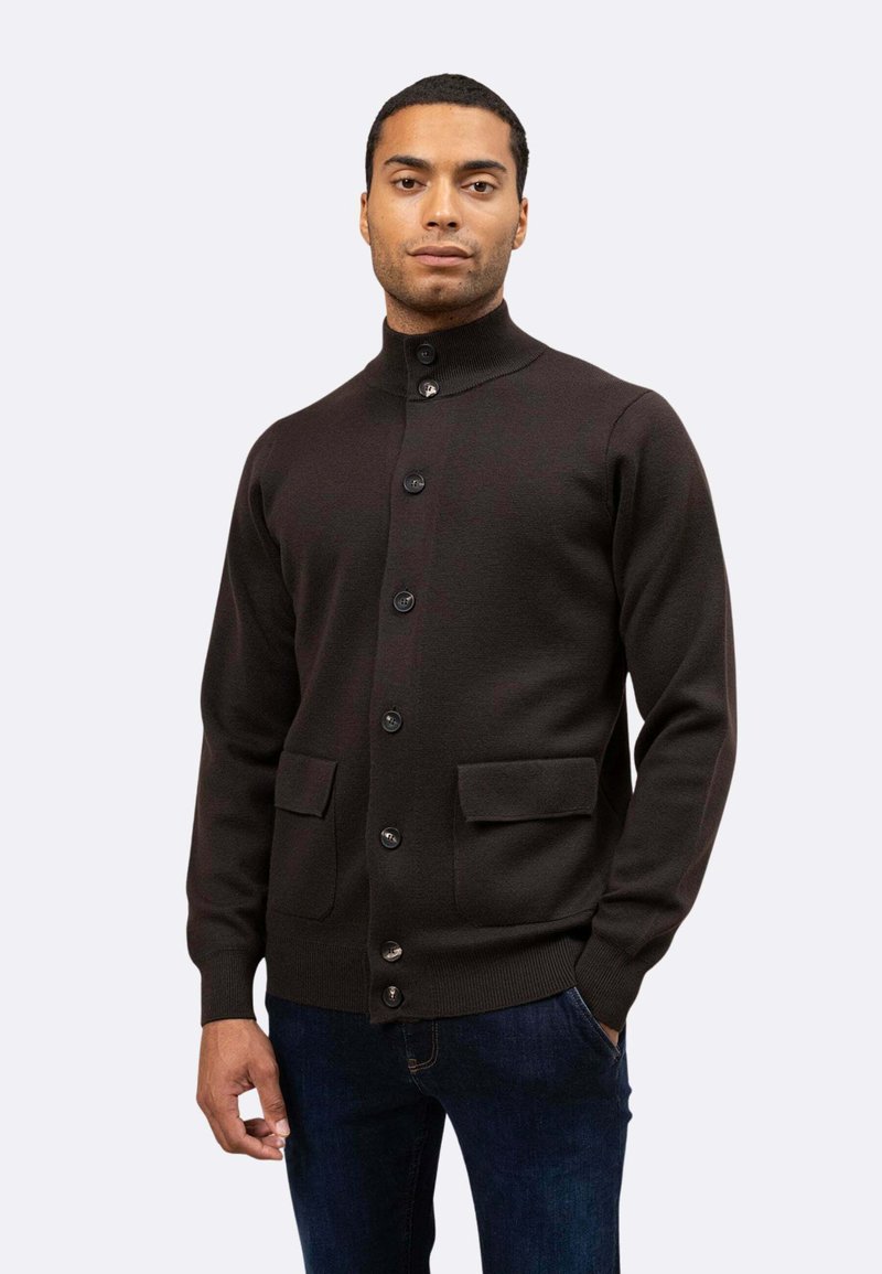 Cardigan marrone scuro con colletto alto, chiusura a bottoni e due tasche frontali. Realizzato in un tessuto morbido con una finitura testurizzata.