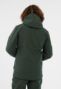 Groene waterdichte jas met een aansluitende capuchon, gestructureerde stof, zijzakken met rits en een gladde afwerking, van achteraf gezien.