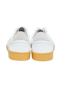 Bílé tenisky s hladkým koženým svrškem, semišovými detaily na patě a texturovanou hnědou gumovou podrážkou, s klasickým nízkým designem.