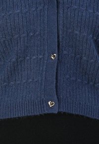 Navy blue knitted cardigan featuring a ribbed texture and silver heart-shaped buttons down the front.