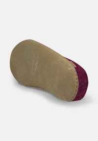 Semelle en daim, avec un dessous beige au toucher lisse et un accent en feutre violet. Forme légèrement courbée avec des détails cousus.