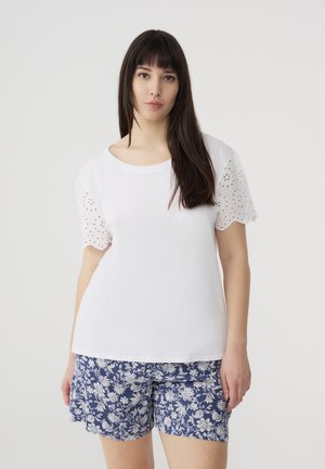 T-shirt bianco in cotone con maniche corte ricamate in pizzo, abbinato a pantaloni corti navy con stampa floreale. Design semplice, dettagli testurizzati sulle maniche.