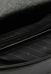 Borsa nera in ecopelle con una superficie testurizzata e un interno foderato caratterizzato da sottili righe verticali. Include una chiusura con zip.
