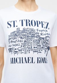 Λευκός T-shirt με μπλε σκίτσο κτιρίων του St. Tropez, κείμενο "ST. TROPEZ, Γαλλική Ριβιέρα, Profiter du soleil" και λογότυπο "MICHAEL KORS".