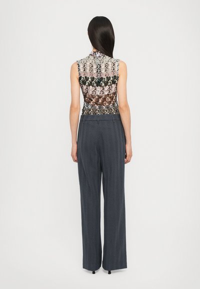 Top fără mâneci, multicolor, cu un model floral; asortat cu pantaloni largi de culoare gri închis, cu textură de herringbone și slituri la tiv.