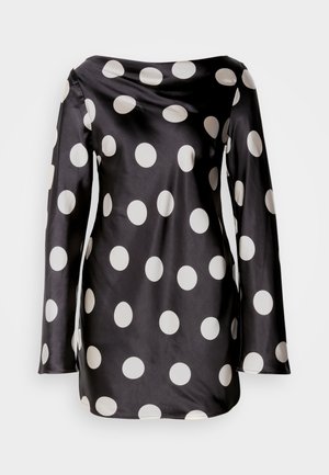 Must mustriga pluus pikade varrukatega, suurte valgete täppidega ja langeva kaelusega. Sile tekstuur ja mugav lõige.