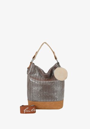 Bolsa tote de color plateado metálico con base de cuero marrón claro, monedero redondo beige brillante y correa marrón desmontable con texto en escritura blanca.