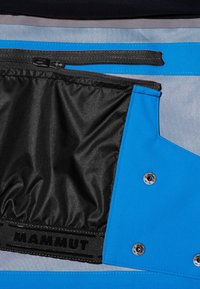 Blue fabric with a matte finish features a black zippered compartment, black lining, and silver hardware. Branding label displayed prominently.