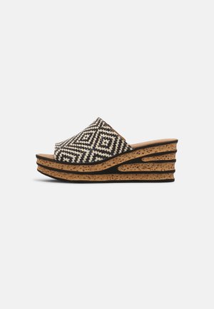 Kile-sandal med øvre del i sort og hvidt stof med geometrisk mønster og lagdelt korksål med sorte accentstriber.