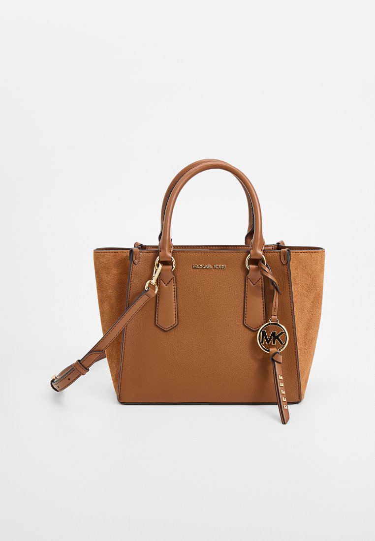 Bolso de mano en color tostado que presenta una combinación de cuero liso y ante, con una forma estructurada, asas dobles y un charm dorado con las iniciales "MK".