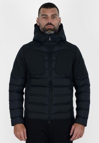 Giubbotto piumino nero con design trapuntato, caratterizzato da un alto colletto, chiusura con zip e doppie tasche frontali. Tessuto morbido e forma aderente.