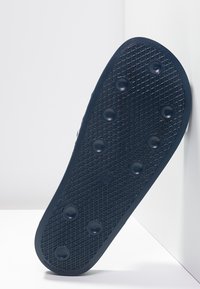 Svart gummiskosula med texturerad yta, som har cirkulära greppmönster och upphöjda knölar för bättre grepp. Vinklad vy mot en ljus bakgrund.