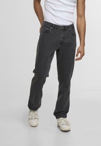 Sorte denimjeans med rett ben-design, fem lommer og knappeslutt. Glatt tekstur og lett falming i stoffet.