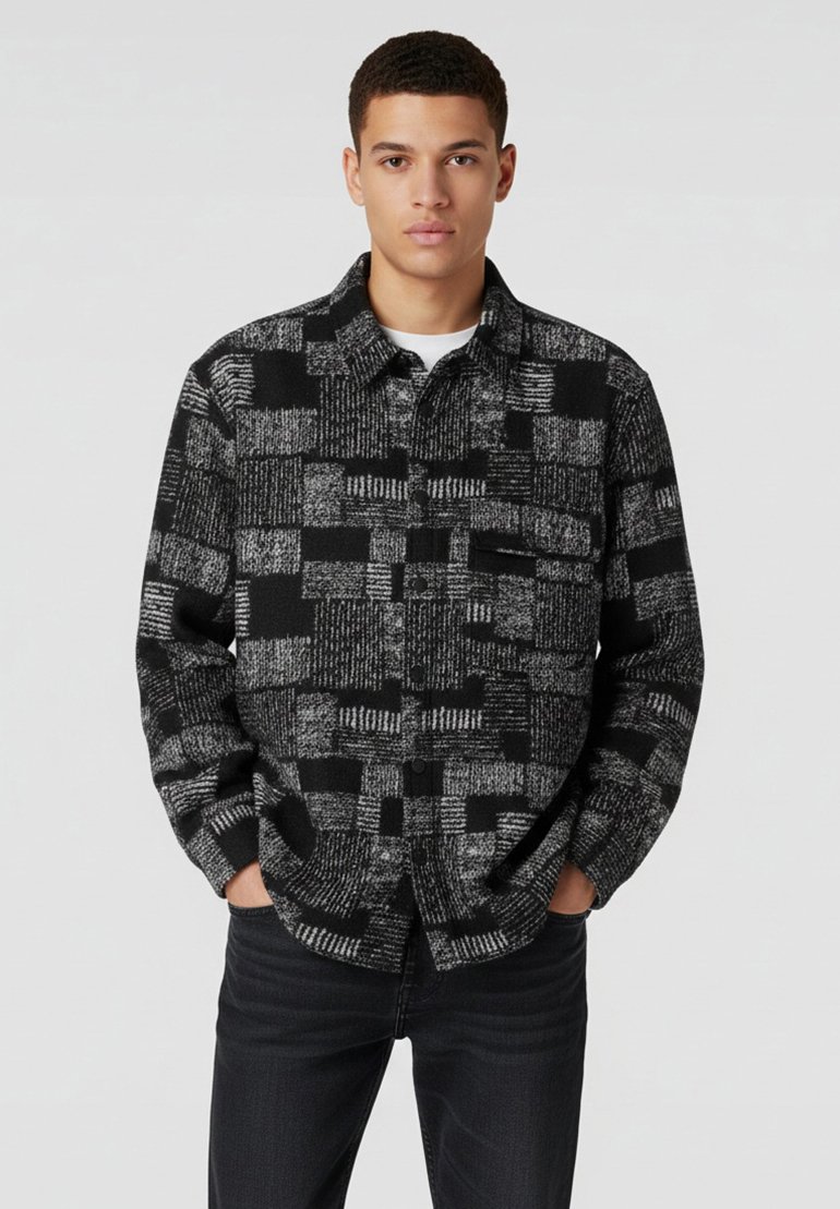 Zwart en grijs geruit shirt met een button-down ontwerp, textuurstof en een borstzak, gecombineerd met donkere jeans.