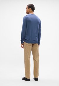 Blue knitted sweater with ribbed cuffs and hem, paired with light brown corduroy pants. Black shoes visible at the bottom.