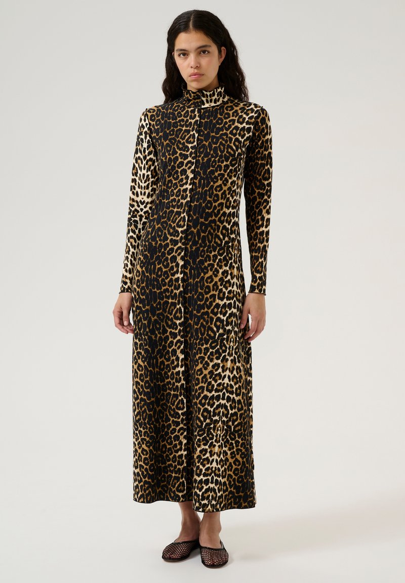 Vestido largo de estampado de leopardo con cuello alto, hecho de tela suave, que presenta patrones en contraste de marrón y negro, combinado con bailarinas de malla negras.