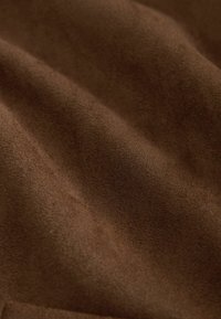 Brown suede fabric with a soft, textured surface, displaying subtle waves and variations in shade, emphasizing its rich color and plush feel.