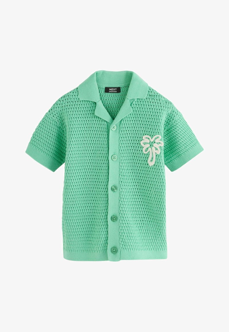 Chemise tricotée manches courtes vert menthe avec motif texturé et écusson blanc de palmier sur la poitrine gauche.