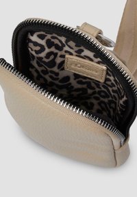 Beige leather bag with a textured exterior, zip closure, and leopard print lining. Features metallic hardware along the zipper.