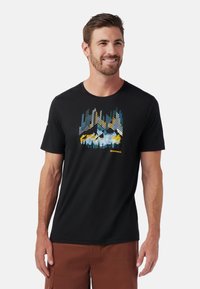 Zwarte t-shirt met korte mouwen, versierd met een kleurrijke bergafbeelding in blauw, geel en groen tinten, gemaakt van zachte stof.