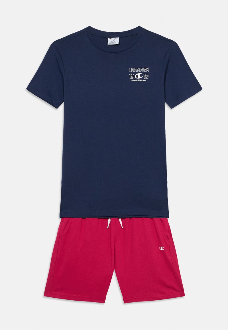 Μπλε ναυτικού βαμβακερό T-shirt με λευκό λογότυπο "Champion 19"· συνδυασμένο με κόκκινα βαμβακερά σορτς με ελαστική μέση και πλαϊνές τσέπες.