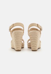 Beige kile-sandaler med vævet jute-detalje på hælen, justerbar ankelrem og glat læder-overdel. Tekstureret sål for bedre greb.