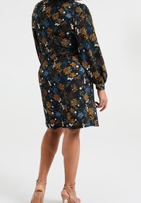 Blumenkleid mit langen Puffärmeln, schwarzem Hintergrund, mehrfarbigen Blumenmustern und einer taillierten Form. Kurze Saumlänge.