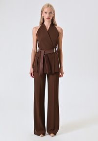 Braunes Halterneck-Top und weit geschnittene Hose Set mit einem taillierten Gürtel und glatter Textur, das eine geschichtete Silhouette mit einem eleganten Finish kreiert.