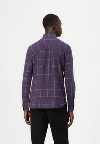 Purple checkered shirt with a grid pattern, long sleeves, soft texture, and a back yoke detail, worn with black pants.
