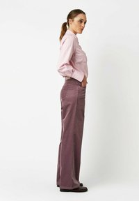 Pink striped shirt paired with wide-leg, muted purple corduroy pants. The outfit features a slim fit and a classic collar design.