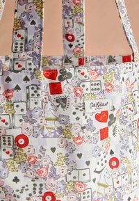 Torba iz blaga z vzorcem igralnih kart, kock, cvetja in šahovskih skakalcev v rdečih, črnih, roza, vijoličnih in zelenih tonih.