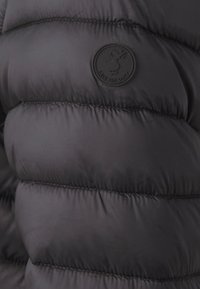 Svart puffjakke med quiltet design, med et sirkulært svart logo-patch merket "SAVE THE DUCK." Glatt, glansfull tekstur.