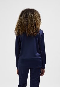 Navy long-sleeve top made from smooth fabric, featuring a relaxed fit, with soft cuffs and a rounded hem at the back.