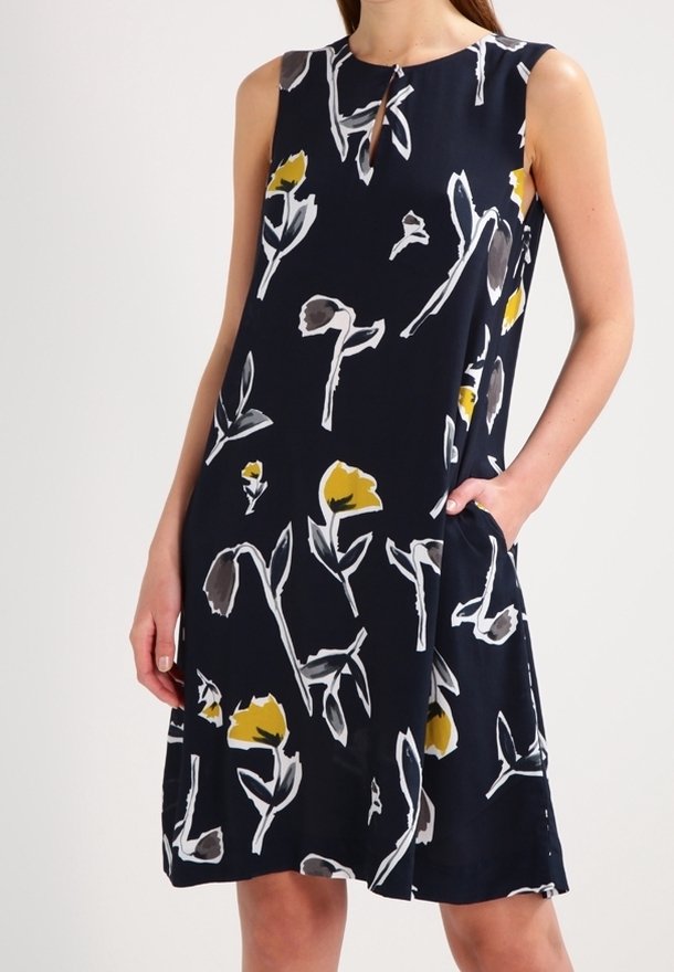 Námořnické šaty bez rukávů s květinovým vzorem v žluté, šedé a bílé barvě. Obsahují výstřih ve tvaru klíčové dírky a boční kapsy. Hladká látka.