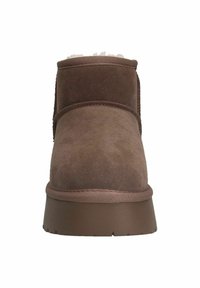 Bottine en suede marron avec un talon bas, doublure douce visible en haut et accents cousus sur les côtés, conçue pour le confort.