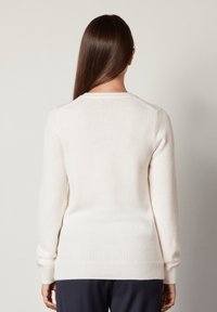 Maglione bianco a maniche lunghe realizzato in morbido tessuto a maglia, con scollo rotondo, polsini a costine e vestibilità rilassata.