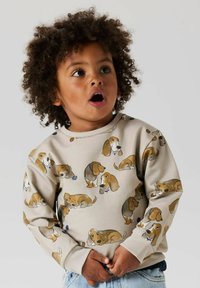 Lichtbeige sweatshirt met een overal print van cartoonhonden in verschillende poses. Ronde hals en geribbelde manchetten, gemaakt van zachte stof.