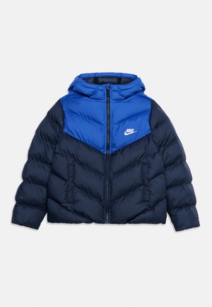 Μπουφάν Nike σε μπλε και μαύρο με κουκούλα, μπροστινό φερμουάρ, πλαϊνές τσέπες και λευκό λογότυπο Nike στο στήθος.