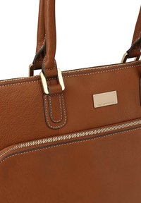 Bruine leren handtas met gouden hardware, bovenste ritssluiting, contrasterende stiksels en een plaquette met merknnaam. Voorzien van dubbele handvatten.